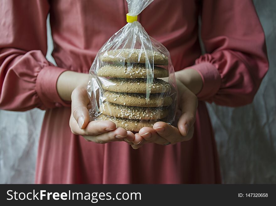 Oat cookies. A girl is holding a package with oatmeal cookies. Closeup front view