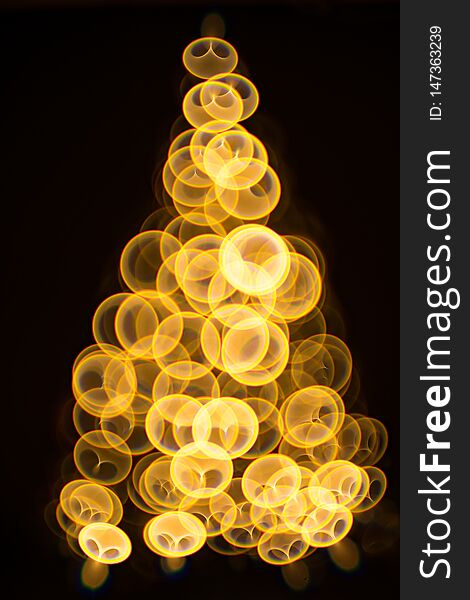 Golden Christmas tree with decorations and lights bokeh in a black background. Golden Christmas tree with decorations and lights bokeh in a black background