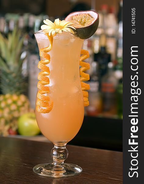 Tropical Cocktail in a hurricaneglass with a blossom, passion fruit and orange paring