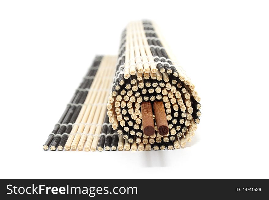 Rolled bamboo mat with a pair of chopsticks isolated on white background. Rolled bamboo mat with a pair of chopsticks isolated on white background