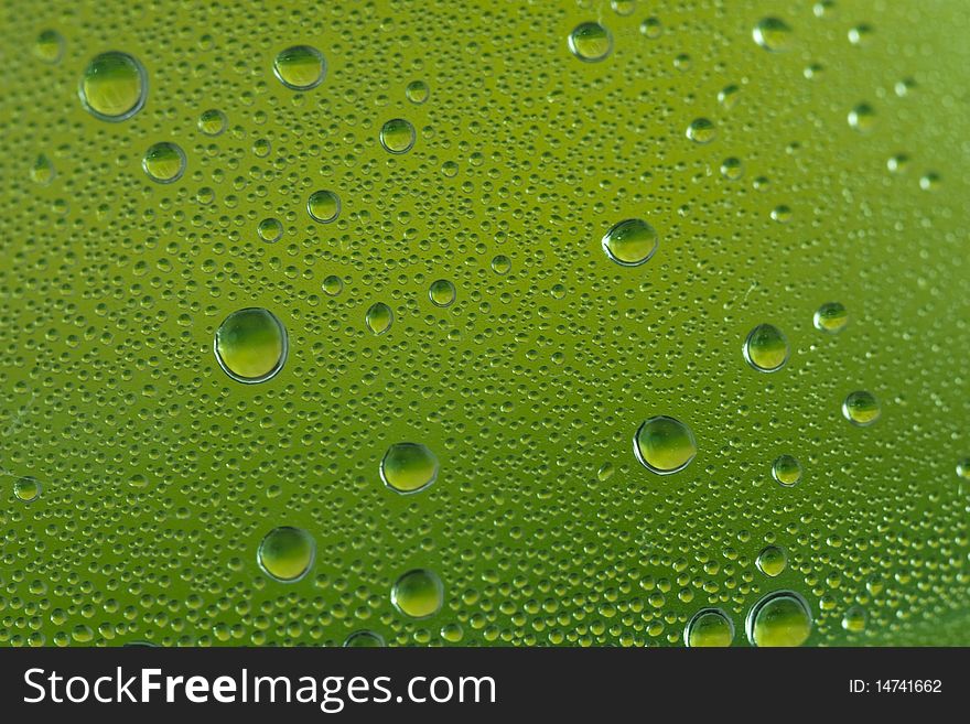A close up shot of green water droplets on a glass. A close up shot of green water droplets on a glass