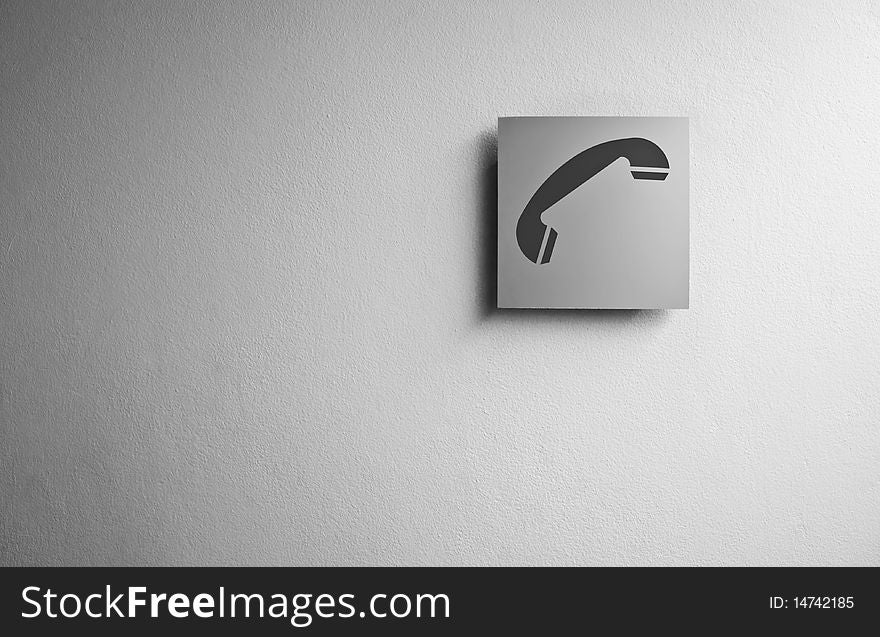 A phone sign over a grey wall