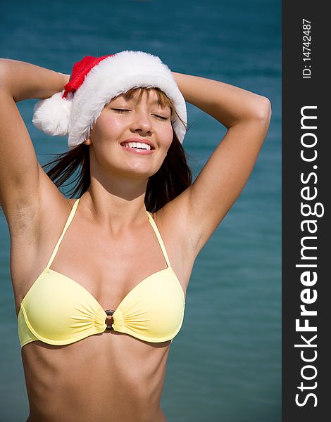 Beautiful young woman in a bikini and hat of Santa Claus sunning at the seaside resort. Beautiful young woman in a bikini and hat of Santa Claus sunning at the seaside resort