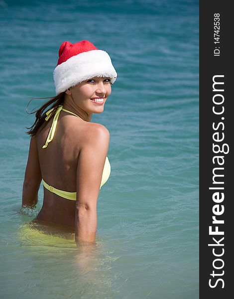 Beautiful young woman in bikini and hat of Santa Claus enters to sea. Beautiful young woman in bikini and hat of Santa Claus enters to sea