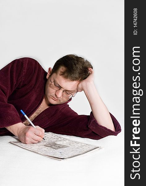 The man in a dressing gown with a crossword puzzle, on a white background.