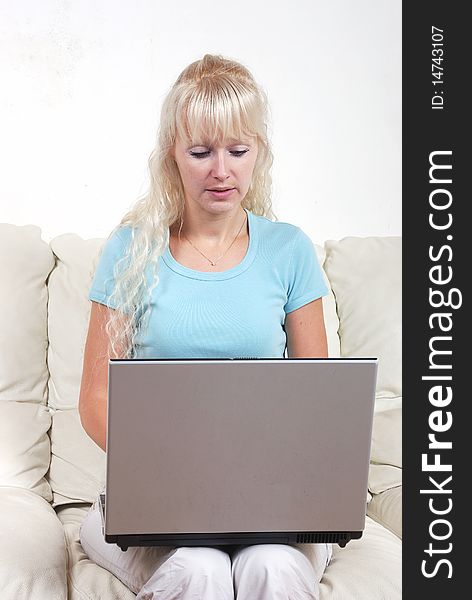 Portrait of blond woman on sofa with notebook computer