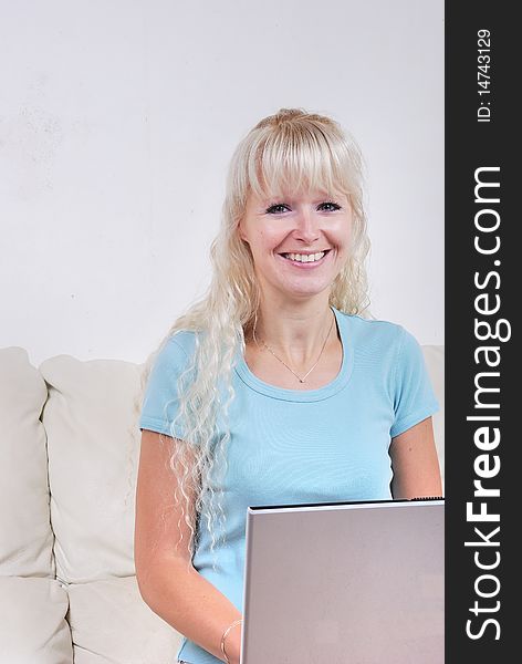 Portrait of blond woman on sofa with notebook computer