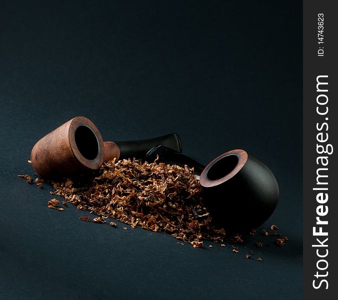 Two pipes and a pile of tobacco, on a black background. Two pipes and a pile of tobacco, on a black background
