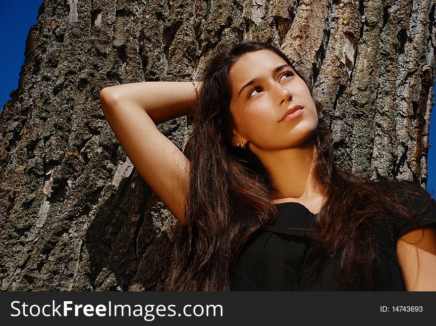 Close Up Of Beautiful Girl Next To A Tree.