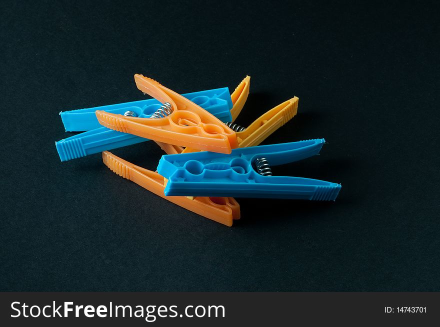 Different colored laundry clips on a black background.