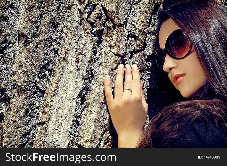 Close Up Of Model In Glasses Next To A Tree.