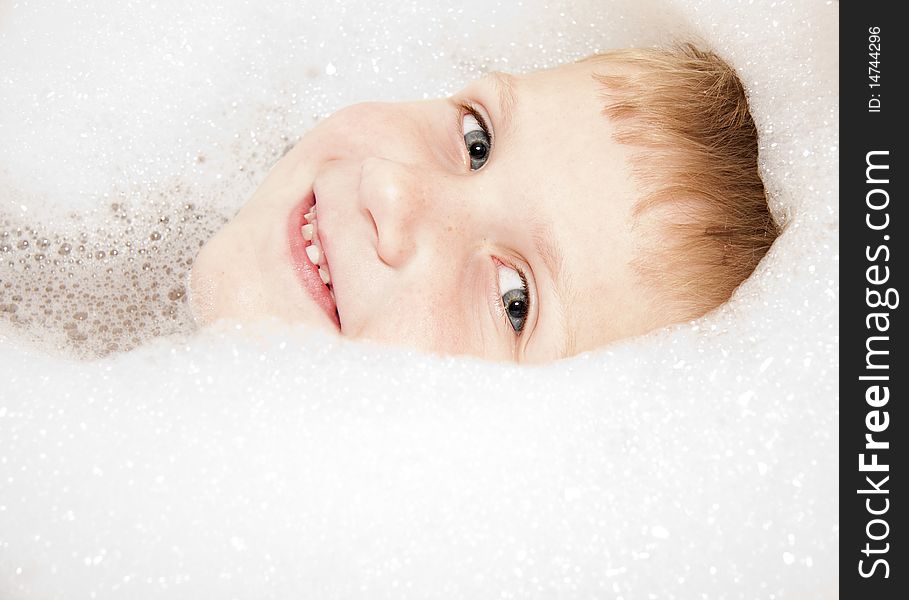 Young blue eyed boy in bubble bath smiling. Young blue eyed boy in bubble bath smiling