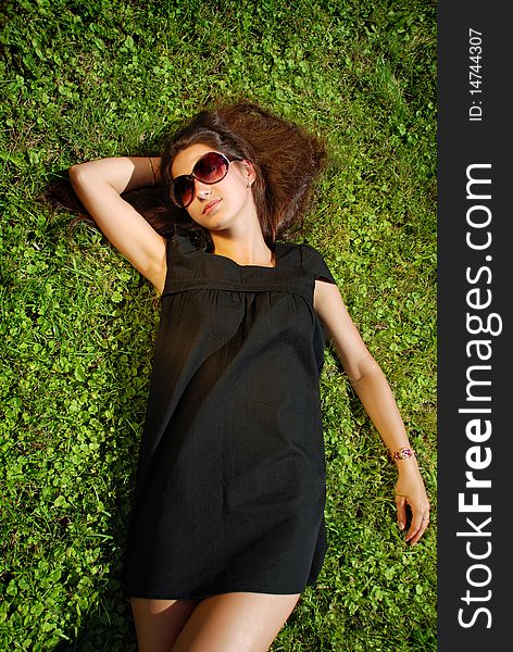 Charming Lady In Black Dress Lying On Grass.