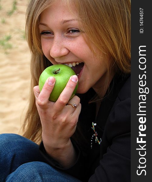 Beautiful happy blond woman bite off green apple