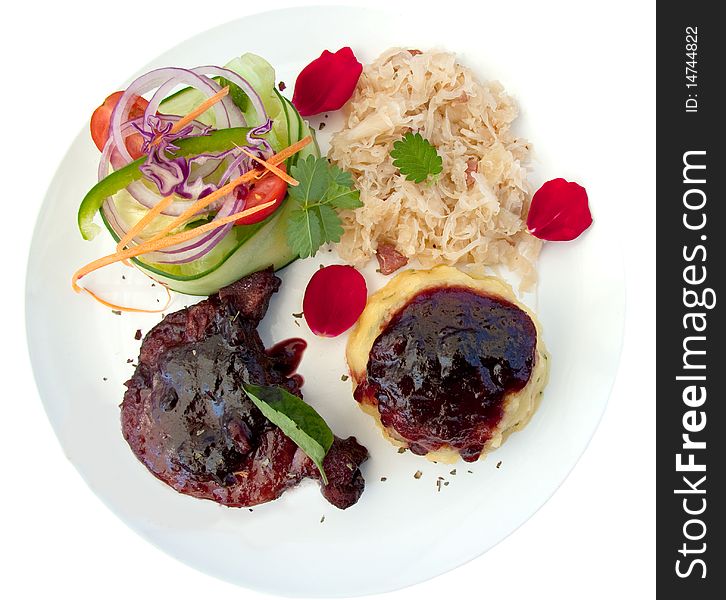 Pork cutlet served with sauerkraut, mash, salad and cranberry sauce garnished with rose petals on white background. Pork cutlet served with sauerkraut, mash, salad and cranberry sauce garnished with rose petals on white background