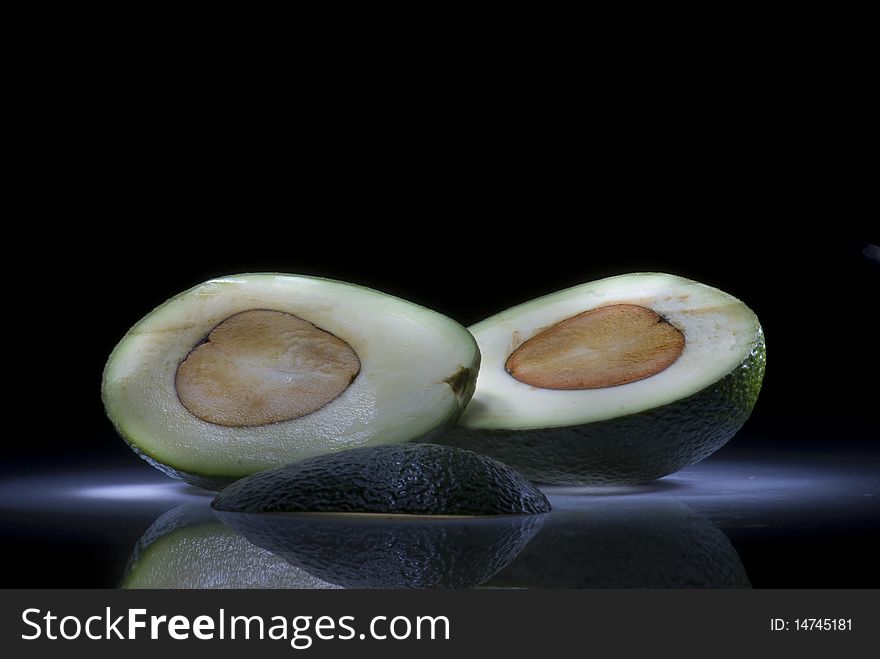 Two slices of avocado on a dark background