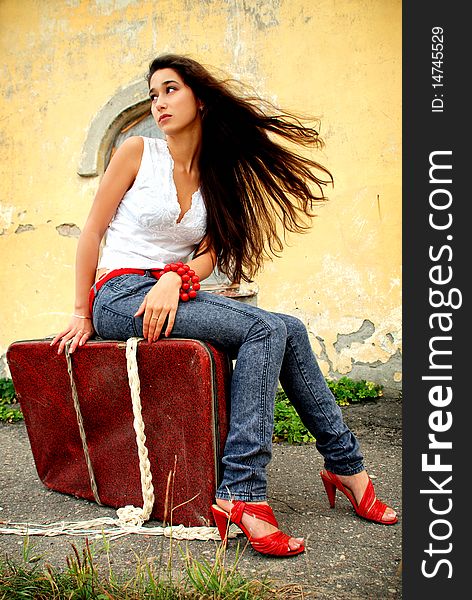 Charming Model Sitting On Red Suitcase.