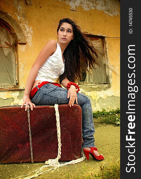 Beautiful Model Sitting On Red Suitcase.