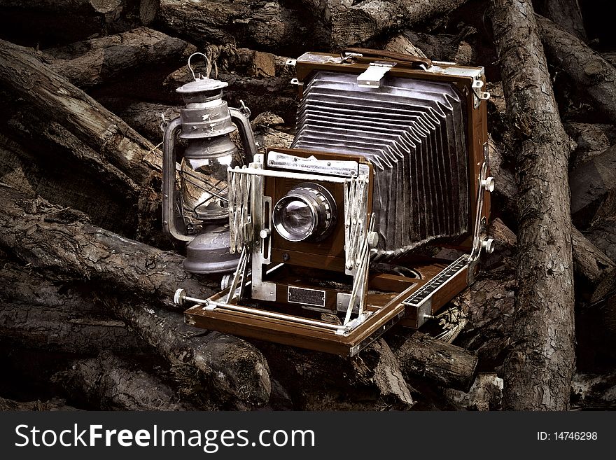 In the pile of wood to be forgotten, old-fashioned camera and lantern