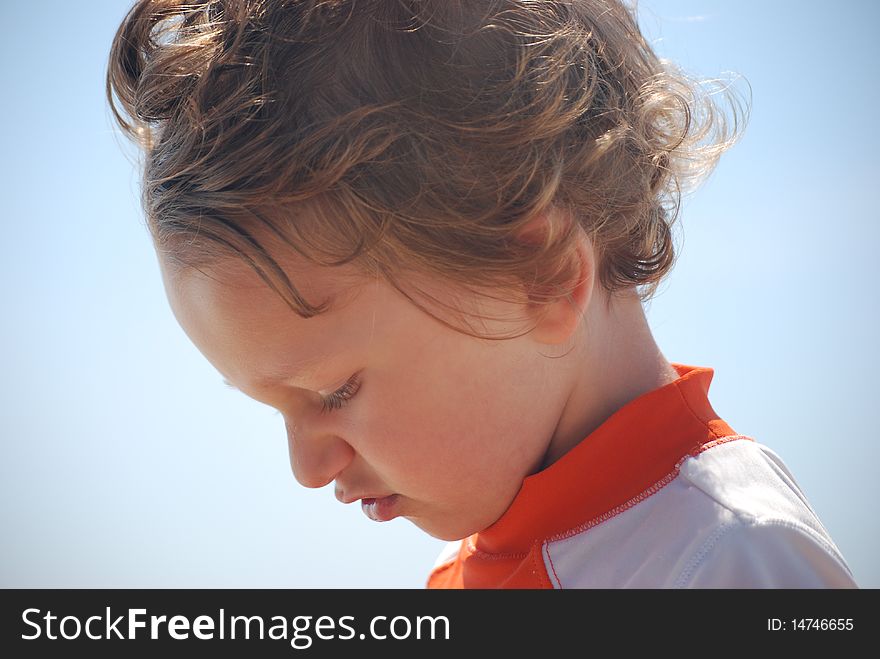 A side profile of a white caucasian toddler boy that is outside with the blue sky in the background. A side profile of a white caucasian toddler boy that is outside with the blue sky in the background.