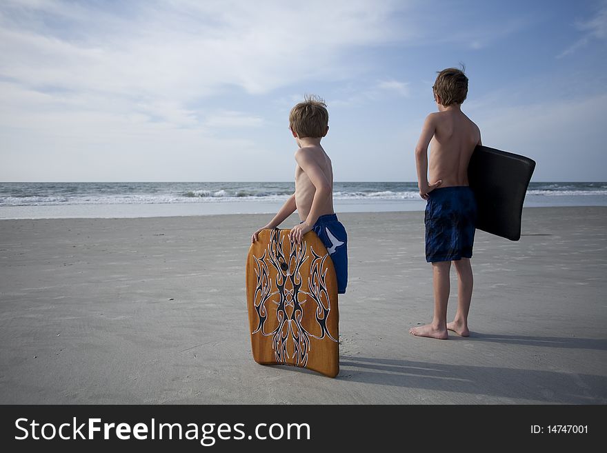 Two young boys at the beach with boogie boards