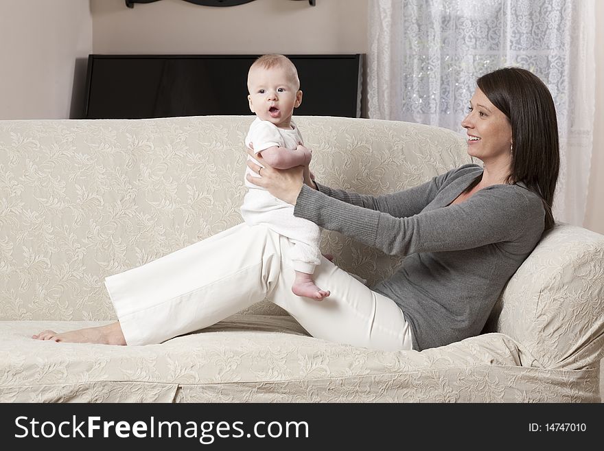 Young mother sitting on a couch with her baby on her knees. Young mother sitting on a couch with her baby on her knees