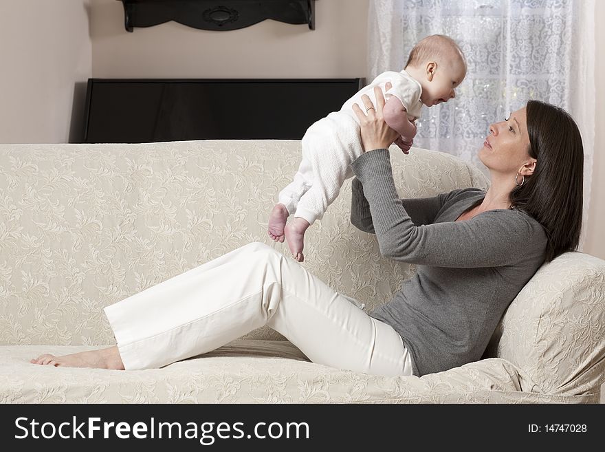 Young mother sitting on a couch with her baby. Young mother sitting on a couch with her baby
