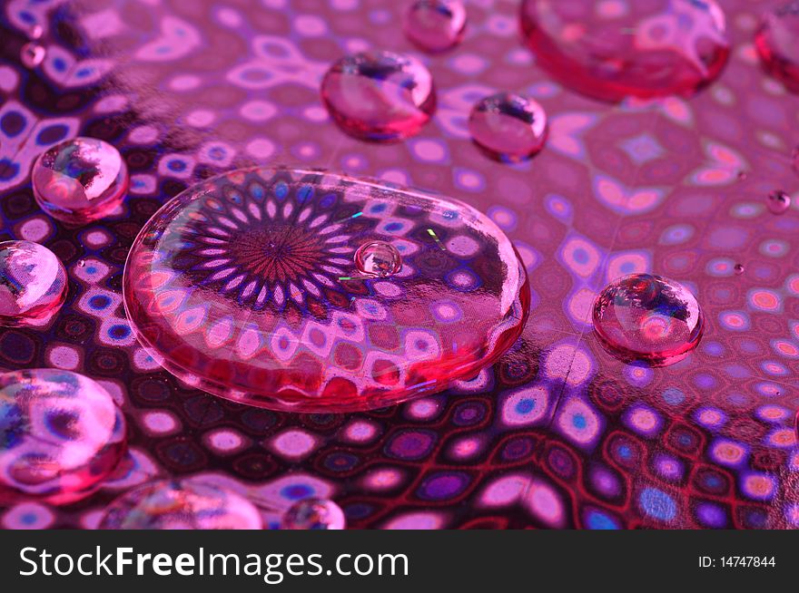 Macro image of water drops on a pink foil patterned backdrop. Macro image of water drops on a pink foil patterned backdrop