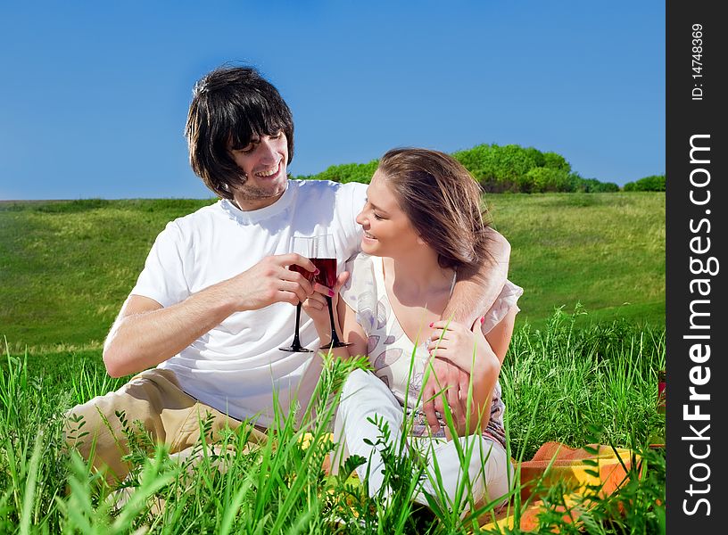 Beautiful girl and boy with wineglasses on grass