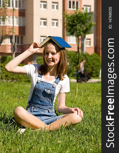 High school student, lying in grass on school campus reading a book. Student studying on the grass. Beautiful young woman reading book at park. High school student, lying in grass on school campus reading a book. Student studying on the grass. Beautiful young woman reading book at park