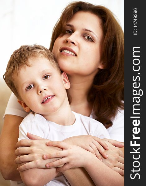 Happy young mother hugging her little son indoor; shallow DOF, focus on boys eyes