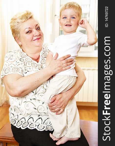 Grandmother holding her grandson indoor; shallow DOF, focus on womans closest eye. Grandmother holding her grandson indoor; shallow DOF, focus on womans closest eye