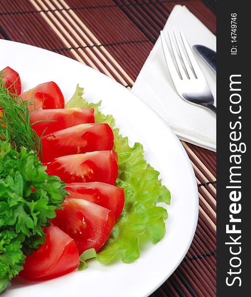 Tomatoes and salad on white dish. Close-up. Tomatoes and salad on white dish. Close-up