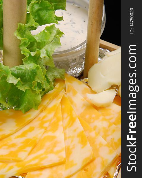 Dutch cheese with white sauce on wooden plate. Closeup