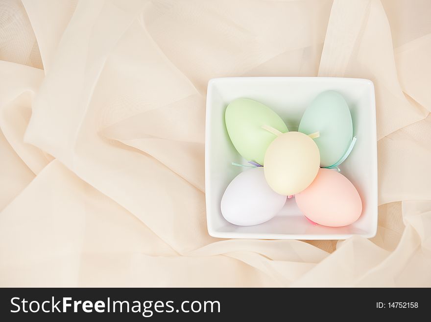 Colorful Easter eggs in square dish on sheer cream fabric. Colorful Easter eggs in square dish on sheer cream fabric