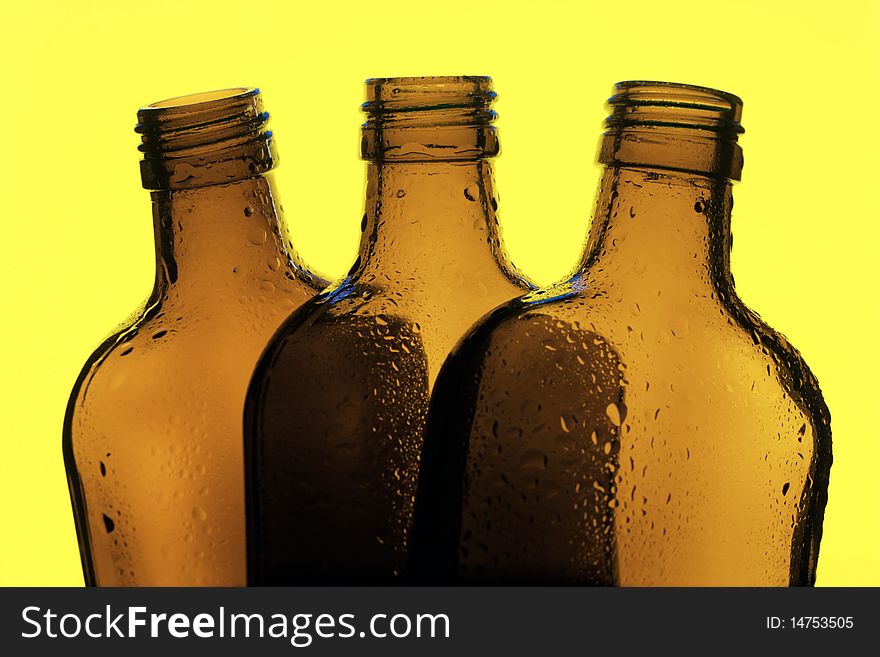 Three glass bottles on a yellow background. Three glass bottles on a yellow background