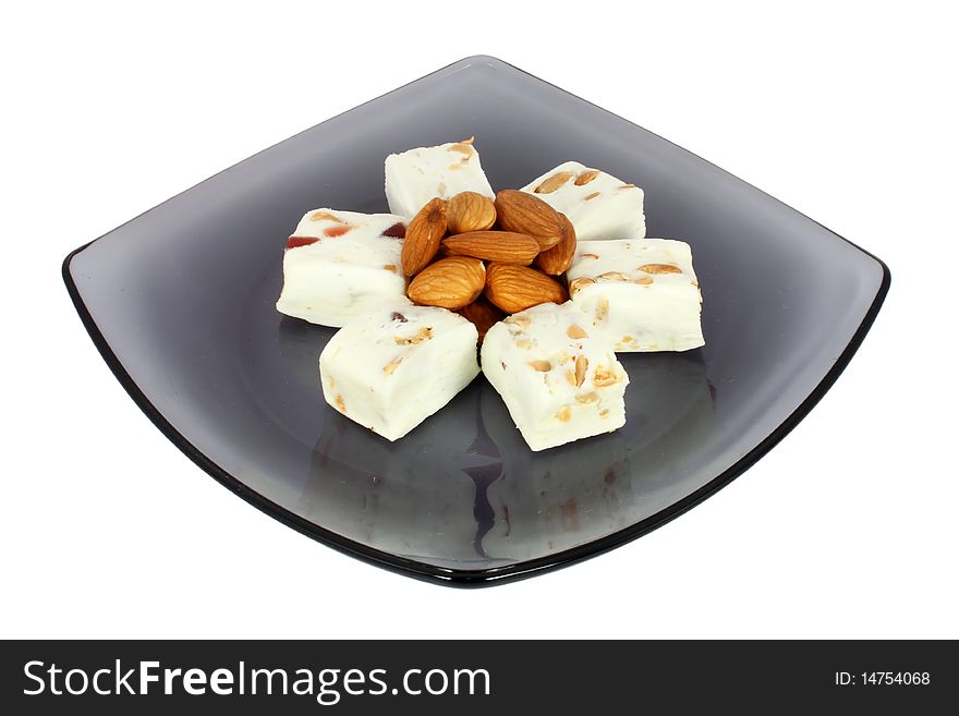 Delicious nougat on black glass plate, isolated on white