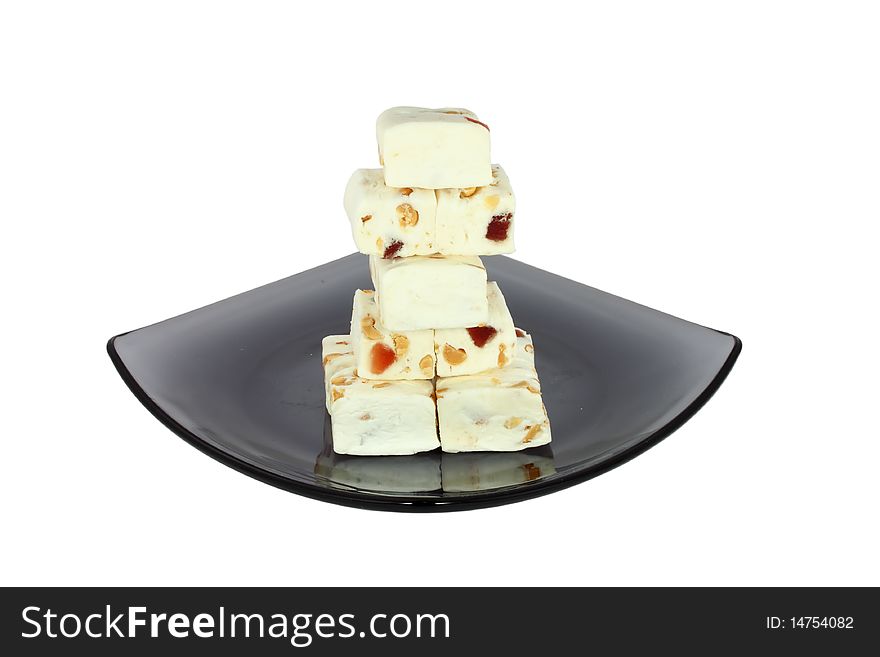 Delicious nougat on black glass plate, isolated on white