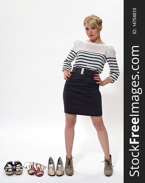 Young blond posing alongside 3 pairs of shoes. Young blond posing alongside 3 pairs of shoes