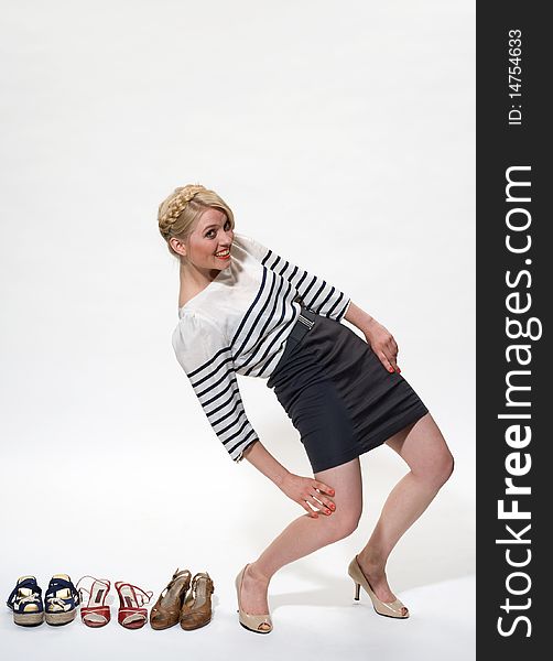 Young blond posing alongside 3 pairs of shoes. Young blond posing alongside 3 pairs of shoes