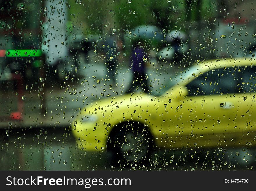 The photo is taken on a rainy day. The yellow car came into the view and the pedestrians holding umbrellas were waling on the sideway. The photo is taken on a rainy day. The yellow car came into the view and the pedestrians holding umbrellas were waling on the sideway.