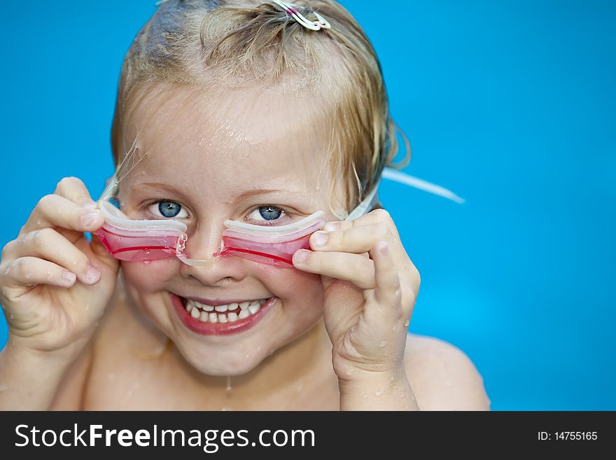 Young pretty girl in swimming-pool holding googles