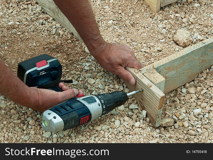 Builder's hands fastening together wooden boards for concrete shuttering. Builder's hands fastening together wooden boards for concrete shuttering.