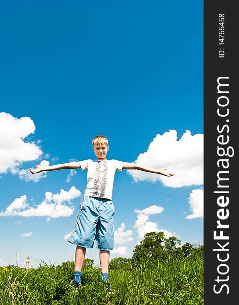 A child on the grass against the blue sky. Sunny summer day.