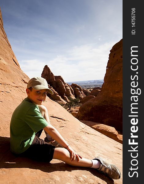 Young boy sitting for a rest while hiking in Arches National Park near Moab UT