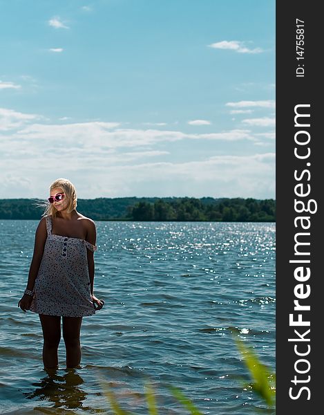 Blond girl standing in river in sunglasses