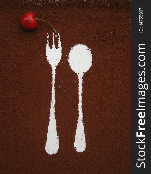 White traces of a fork and a tea spoon left on cocoa with cherry on a brown background. White traces of a fork and a tea spoon left on cocoa with cherry on a brown background