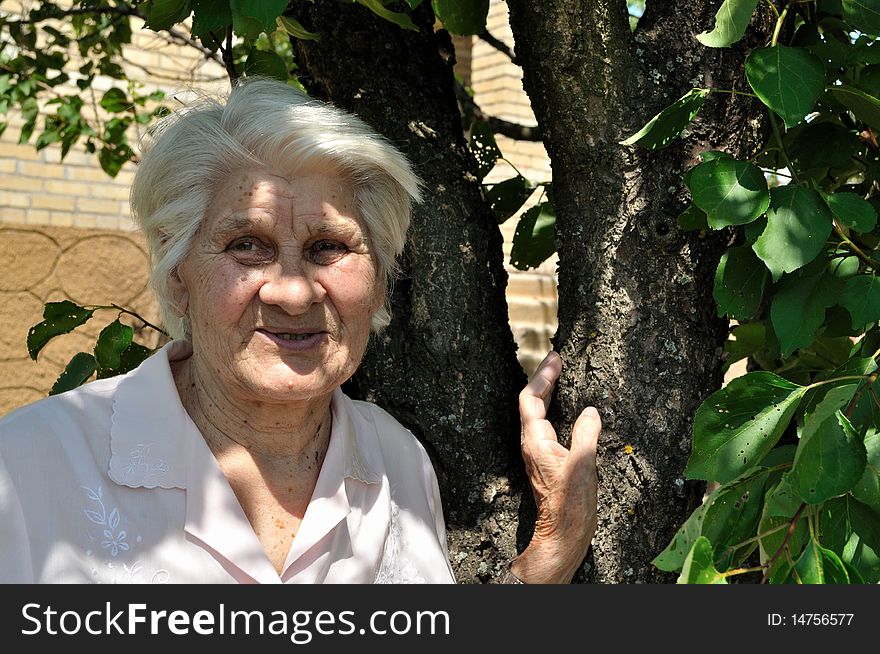 Mature woman standing in a garden near the house. Mature woman standing in a garden near the house