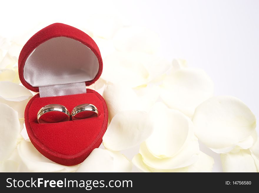 Matching rings in a heart shapped valvet box and in white background with white rose petals. Matching rings in a heart shapped valvet box and in white background with white rose petals