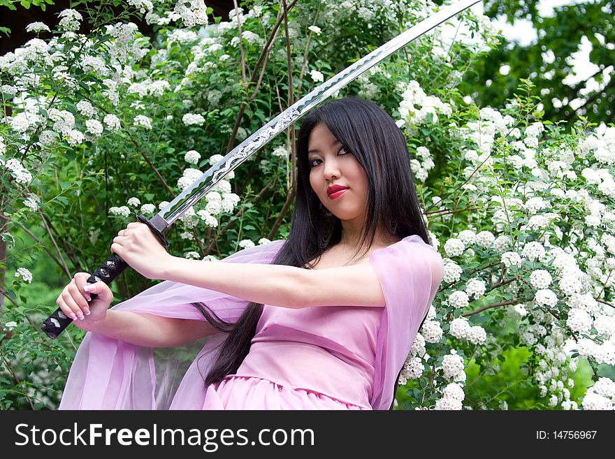 Beutiful japanese woman in pink dress wields a sword